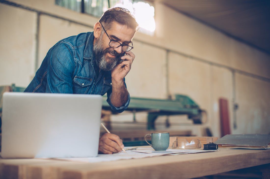 man on the phone in a workshop with a laptop