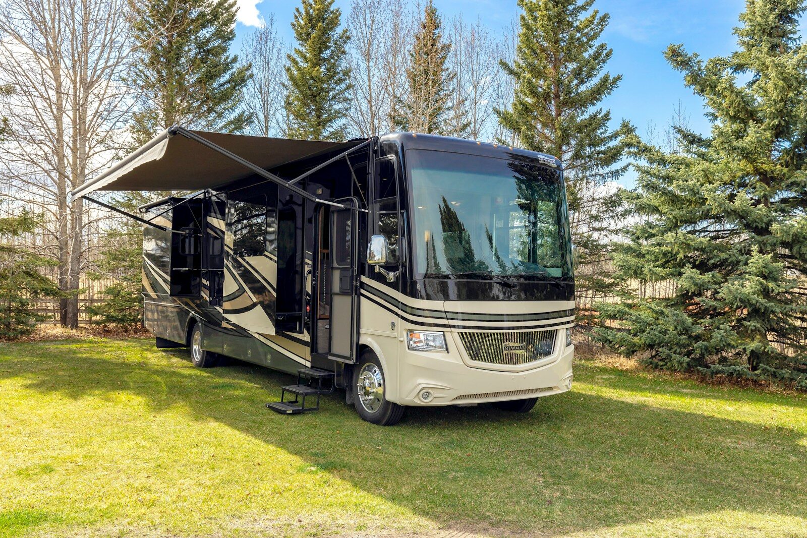 a motor home parked in the grass near some trees